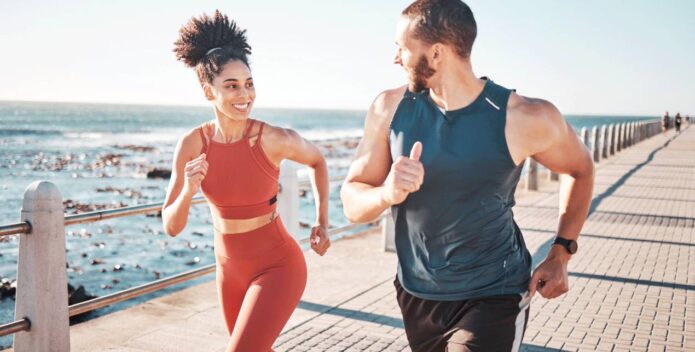 A man and woman jogging by the ocean, revitalized after a visit to the IV drip bar.