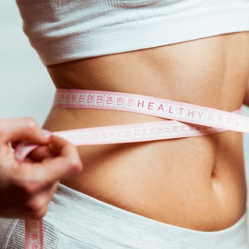 A woman measures her waist