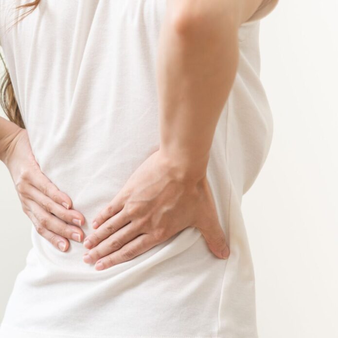 A woman with back pain holding her hands, seeking drip hydration and nutritional IV therapy services.