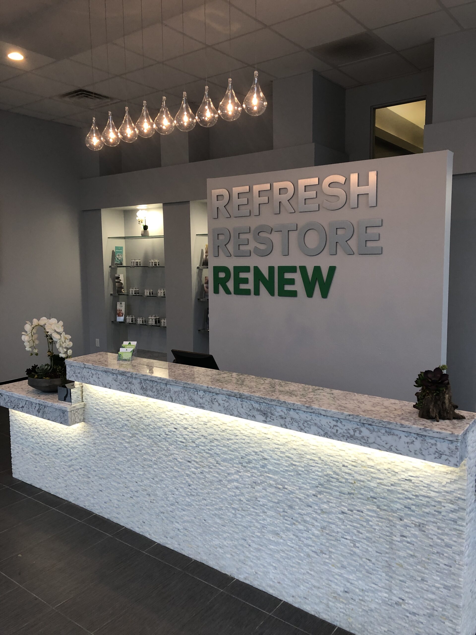 A reception area with a sign that says refresh restore renew, offering nutritional IV therapy and drip hydration.