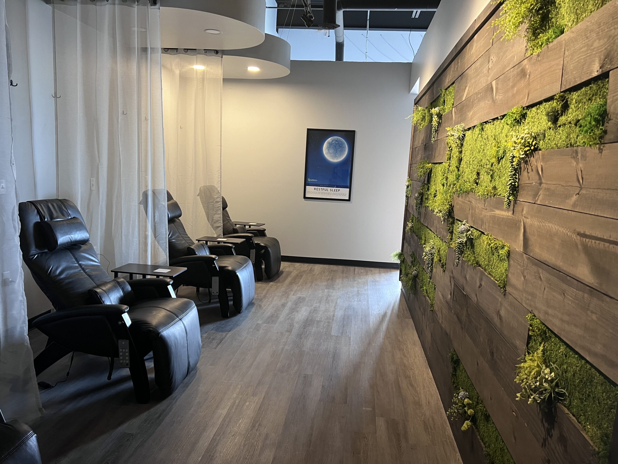 A room with chairs and a wall covered in moss offering nutritional IV therapy.