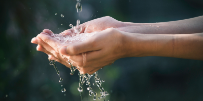 Hands cupped together catching and holding flowing water.